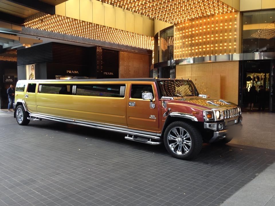 The Golden Sunset gold stretch Hummer limousine outside a lit building at night