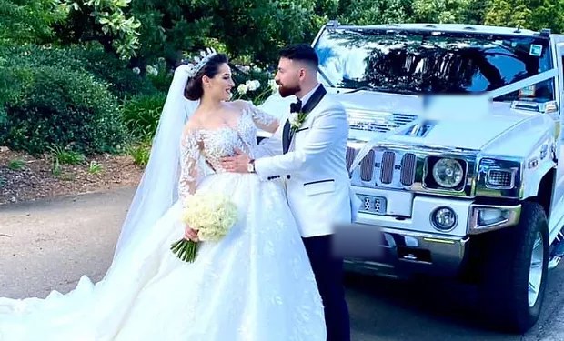 A couple beside the Pearl White stretch Hummer limousine on their wedding day